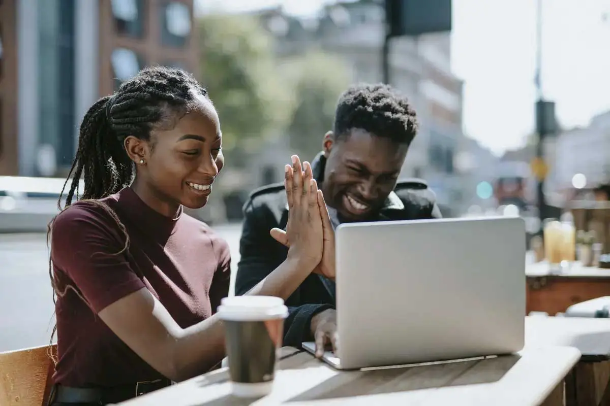 Two students having coffee and working on laptop